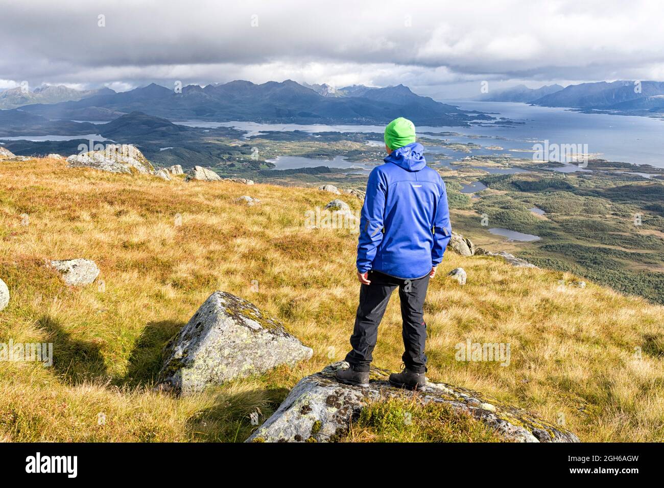 Un homme se dresse au sommet de Vetten et regarde l'archipel de Vesterålen et l'Eidfjord. , Bø, Vesterålen, Nordland, Norvège, Banque D'Images