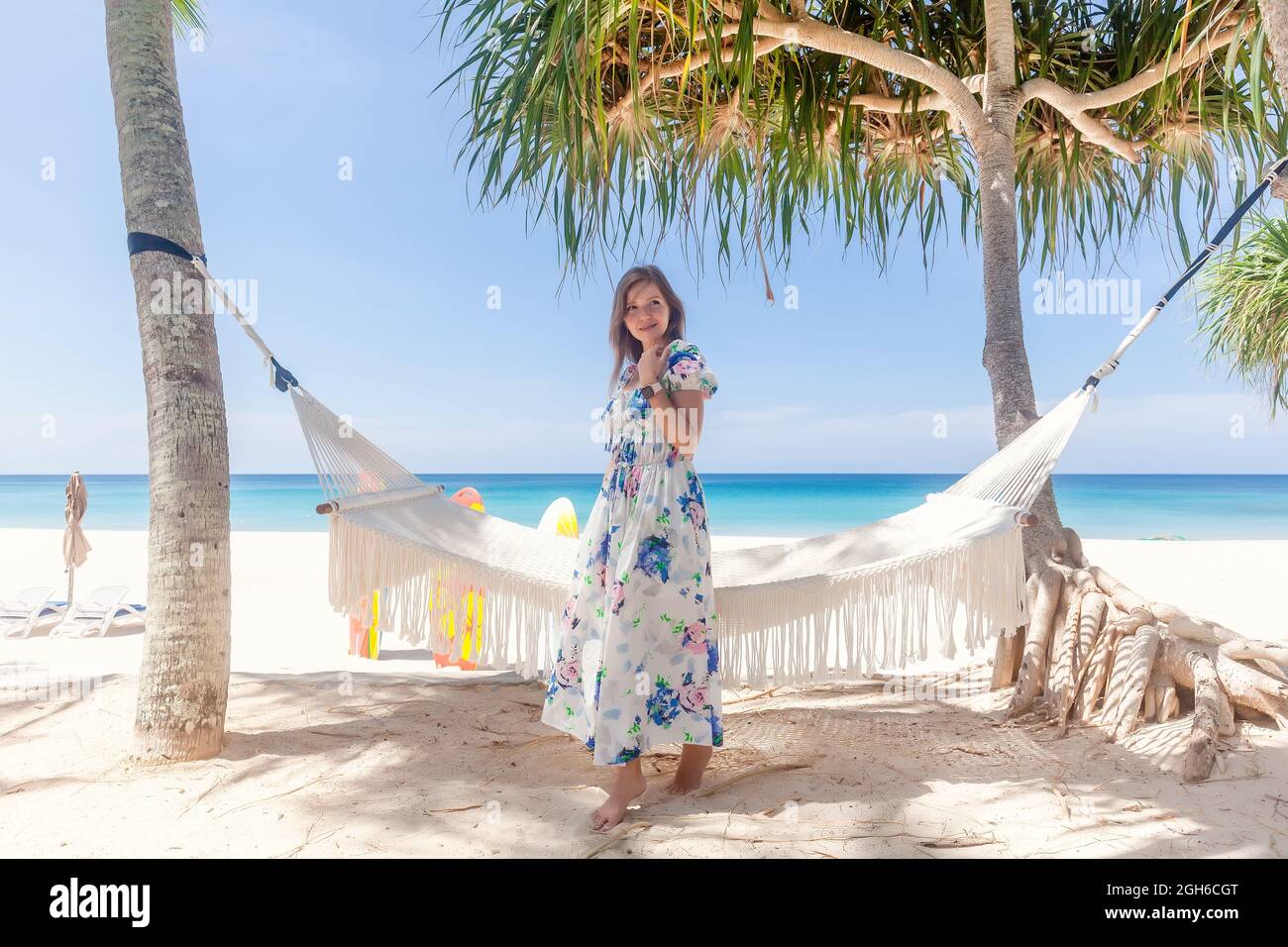 Jeune femme en robe debout près de Hammock entre les palmiers Banque D'Images
