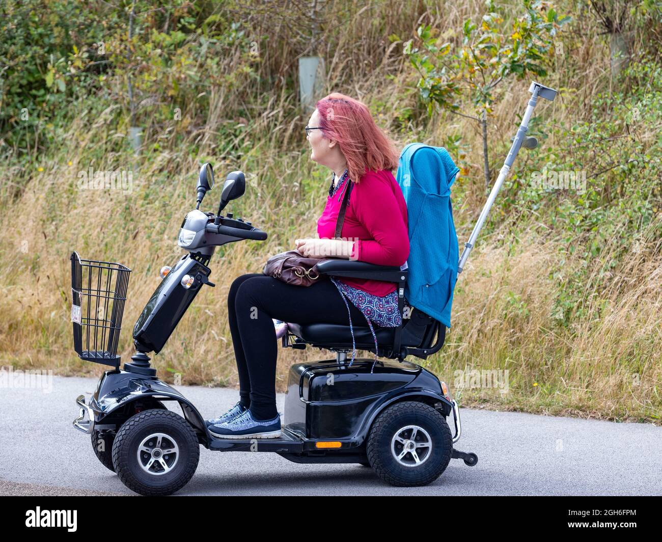 Une dame dans un scooter de mobilité regarde le Tour de Grande-Bretagne course de cycle 2021 comme il est passé par Camborne dans les Cornouailles. Banque D'Images