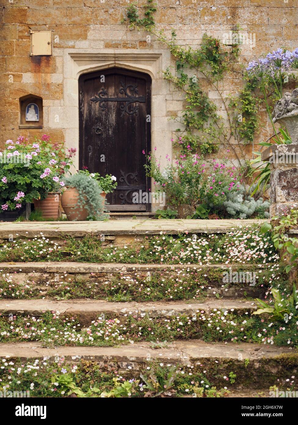 Une maison de campagne, montrant des marches surcultivées menant à une porte, Coton Manor, Northamptonshire, Royaume-Uni Banque D'Images