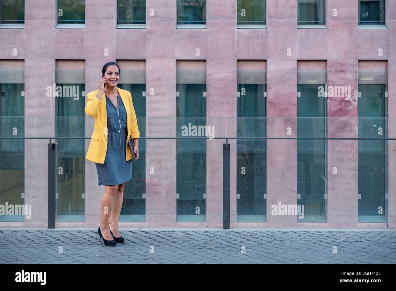 Femme d'affaires caucasienne avec téléphone mobile et ordinateur à l'extérieur. Banque D'Images