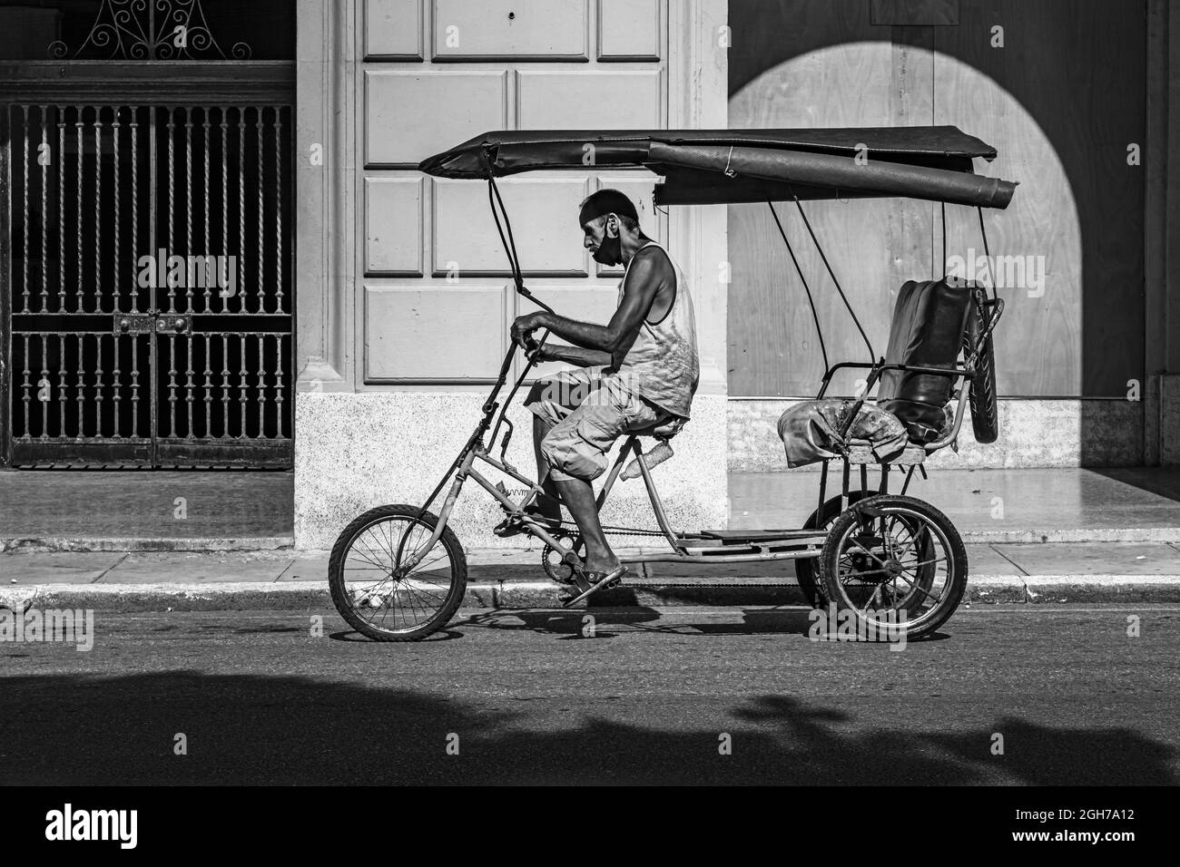 Un homme sur son vélo sur le chemin de trouver de nouveaux clients avec son taxi dans la vieille havanna, cuba Banque D'Images