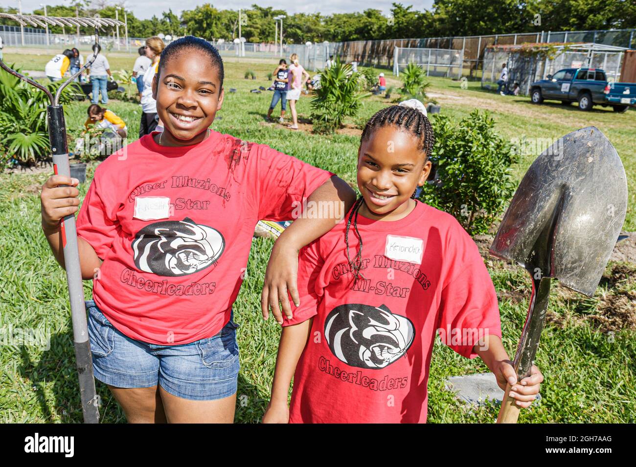 Miami Florida, bénévoles bénévoles bénévoles travail d'équipe travaillant ensemble pour aider les élèves, filles noires amis enfants aménagement paysager plantation Banque D'Images