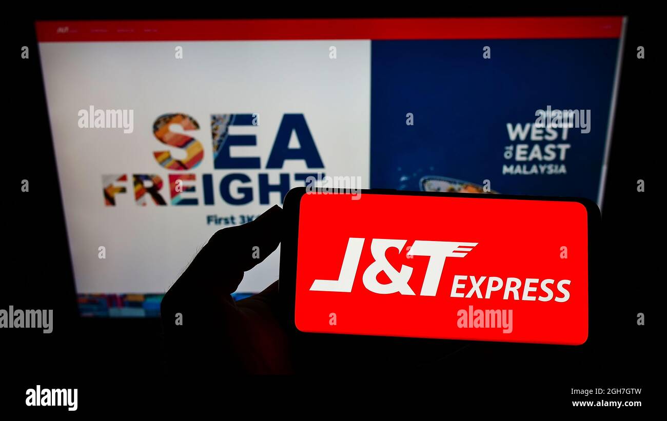 Personne tenant un téléphone portable avec le logo de la société indonésienne PT Global Jet Express (JT) à l'écran en face de la page Web. Mise au point sur l'affichage du téléphone. Banque D'Images