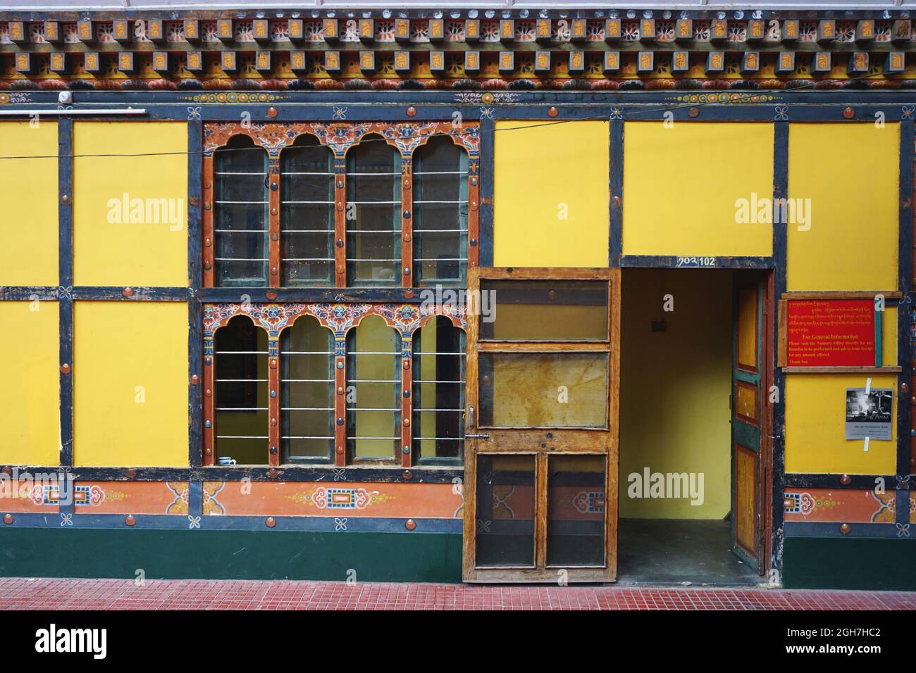 Mur jaune avec porte ouverte et boiseries peintes élaborées au Thangtong Dewachen Dupthop Nunnery, Thimphu, Bhoutan. Architecture bhoutanaise typique. Banque D'Images