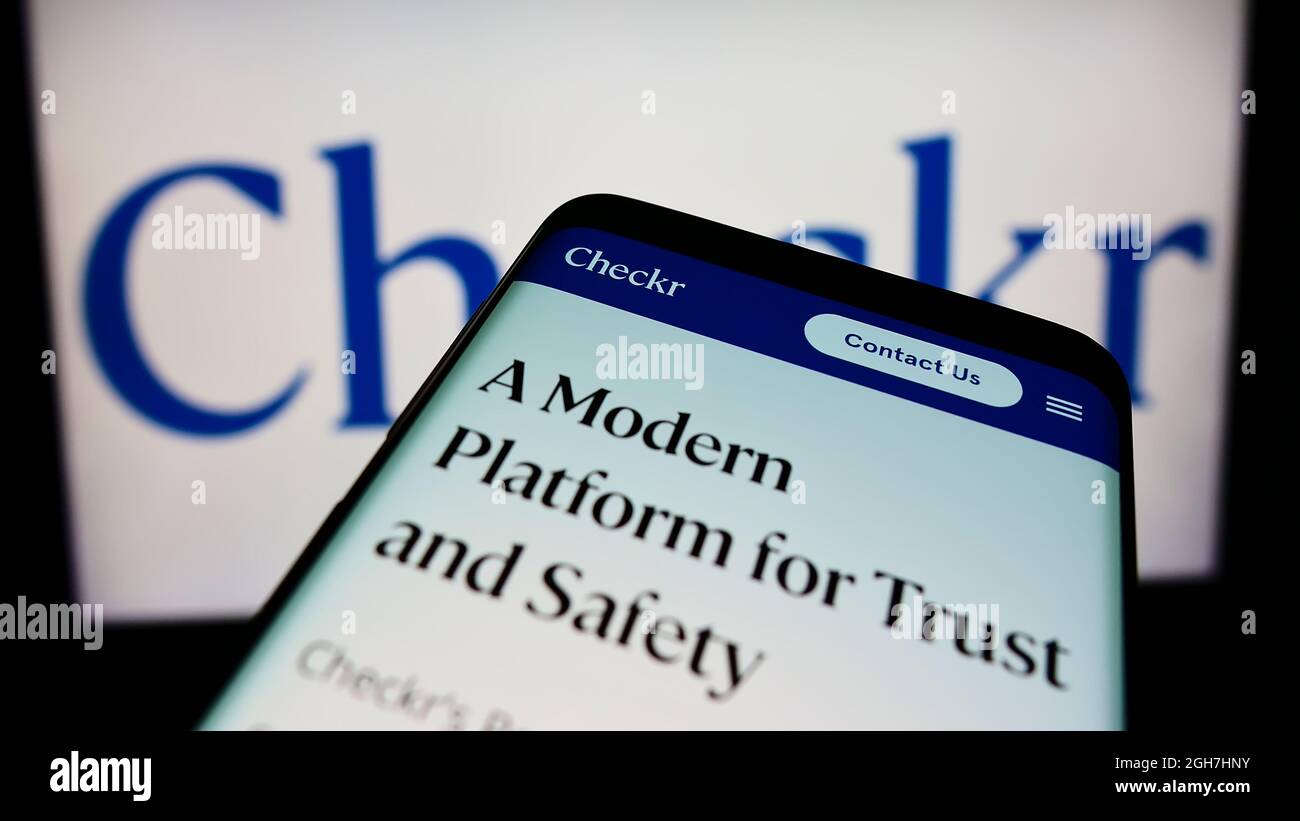 Smartphone avec le site Web de la société de vérification des antécédents américaine Checkr Inc. À l'écran devant le logo de l'entreprise. Faites la mise au point dans le coin supérieur gauche de l'écran du téléphone. Banque D'Images