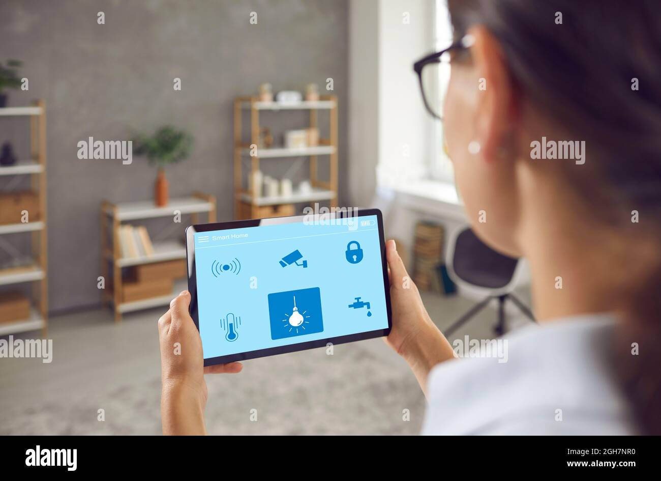 Une femme contrôle l'alimentation électrique dans sa Smart House à l'aide d'une application sur une tablette numérique Banque D'Images