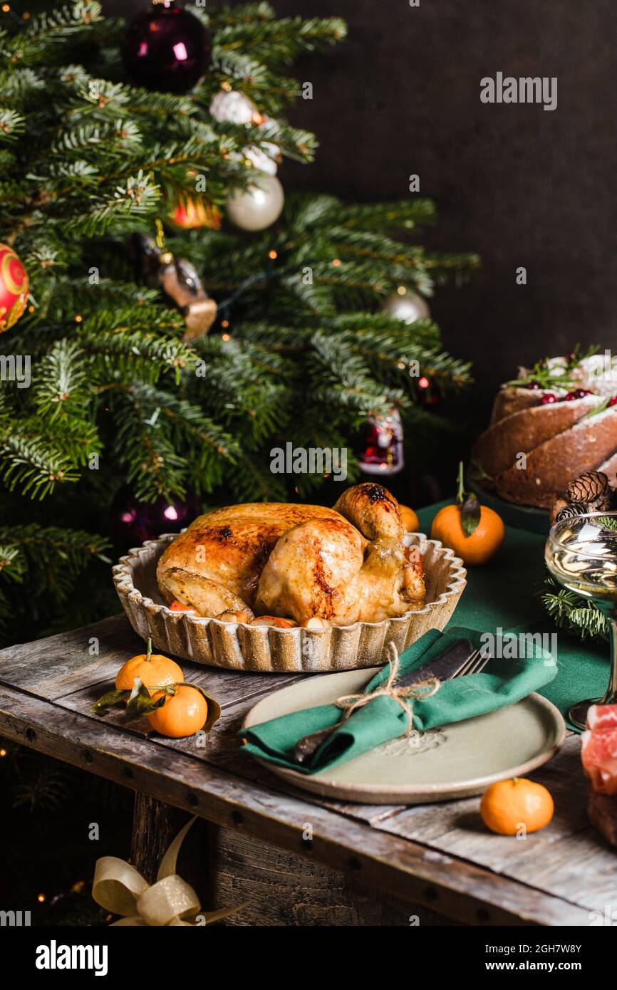 Poulet cuit comme plat de vacances principal sur une table décorée de guirlande. Concept de fête familiale nouvel an de Noël. Banque D'Images