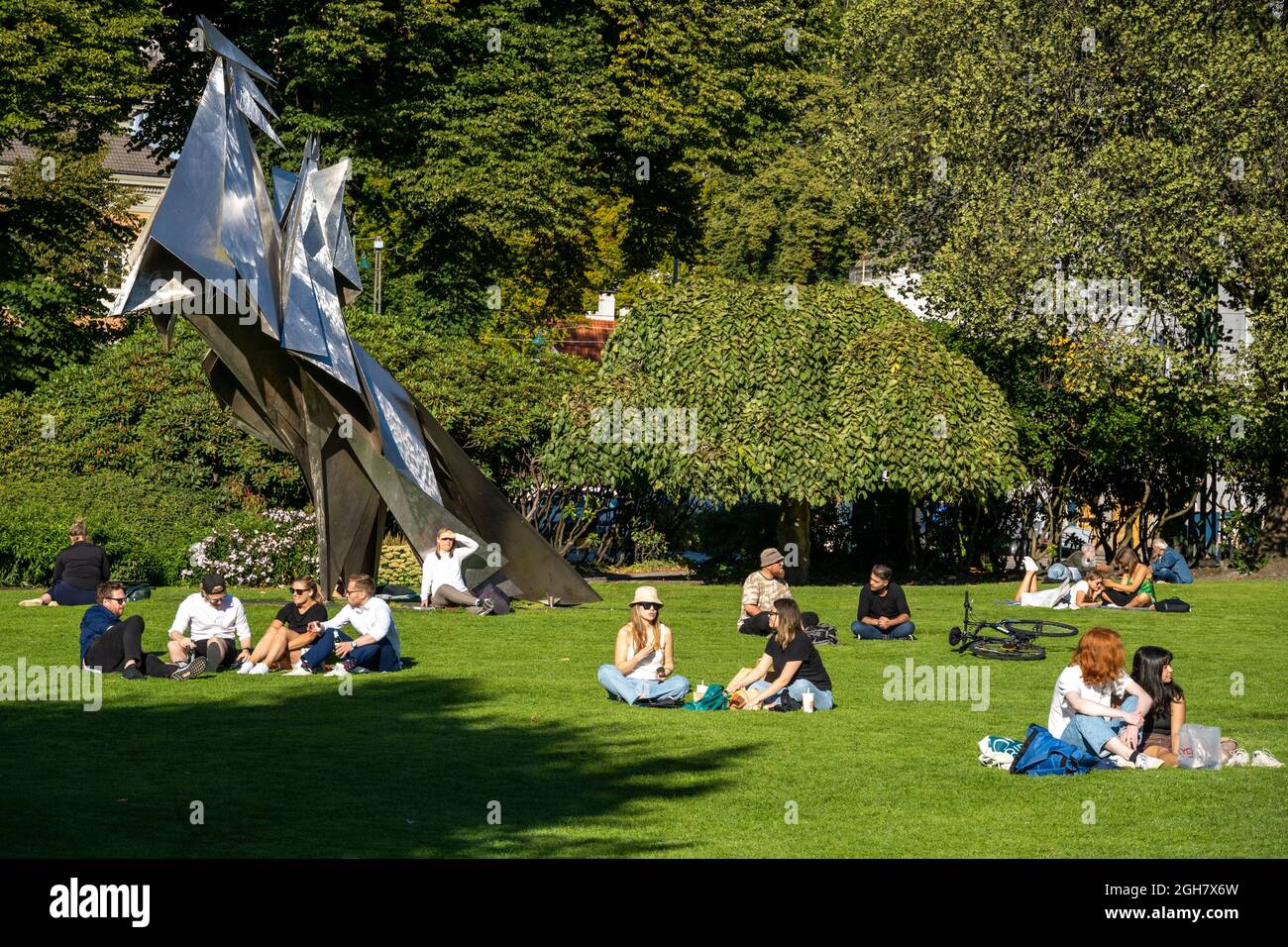 Les gens qui profitent du soleil à côté d'une sculpture du fondateur de Bergen, le roi viking Olav Kyrre sur son cheval par Knut Steen, Bergen, Norvège Banque D'Images