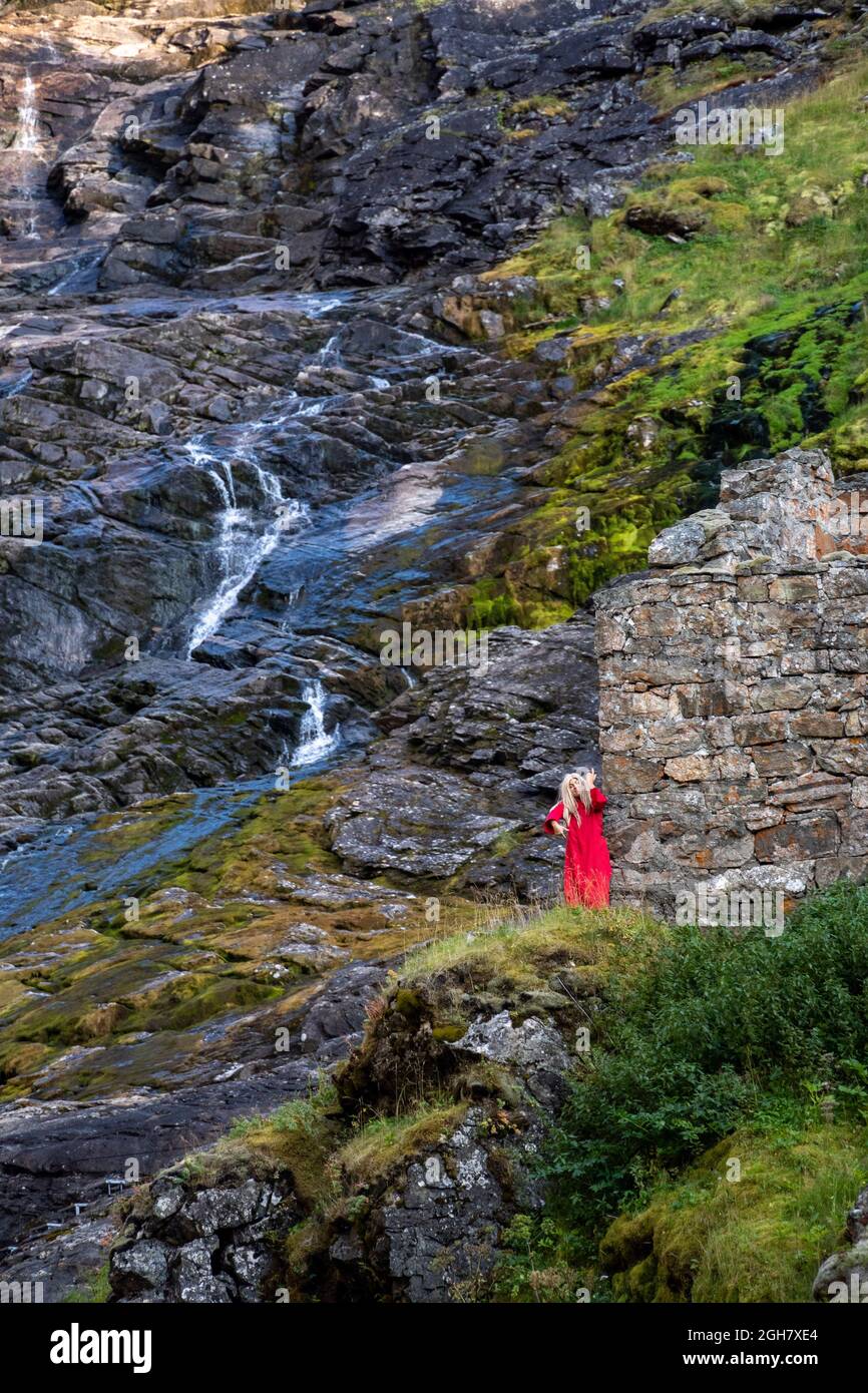 Danseuse vêtue d'une robe rouge se produit à la cascade de Kjosfossen - Norvège Flamsbana - le chemin de fer de Flam, Flam, Norvège, Europe Banque D'Images