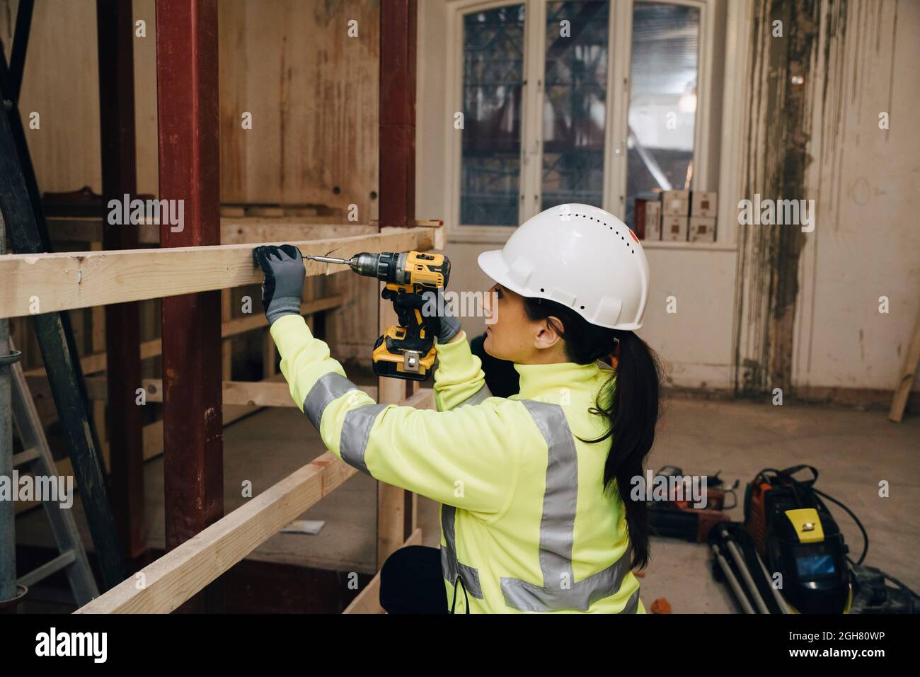 Femme travaillant sur un chantier de construction utilisant une perceuse sur une planche en bois Banque D'Images