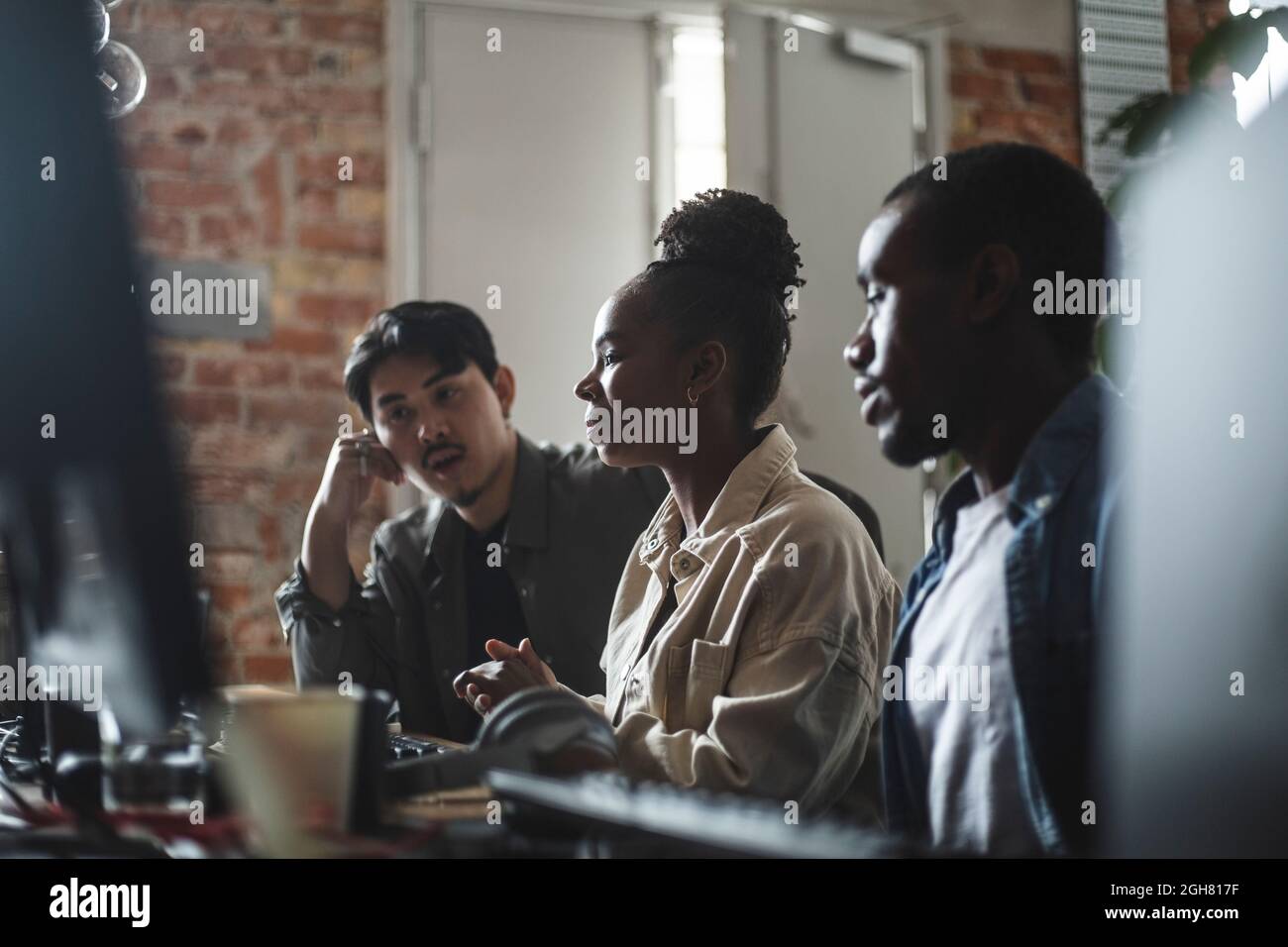 Hacker féminin discutant avec un collègue masculin sur l'ordinateur dans le bureau de création Banque D'Images
