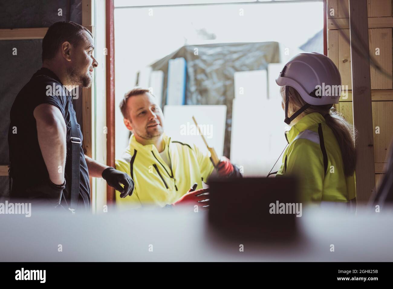 Hommes et femmes ouvriers de la construction discutant ensemble sur le chantier de construction Banque D'Images