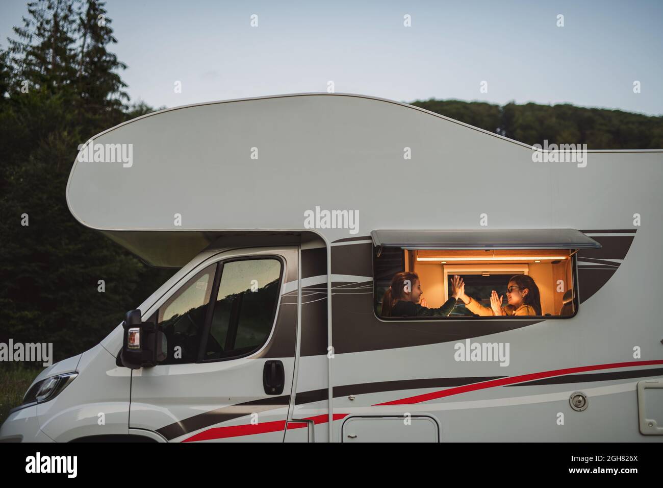 Joyeuses petites filles jouant à des jeux à l'intérieur de la caravane le soir, vacances en famille. Banque D'Images