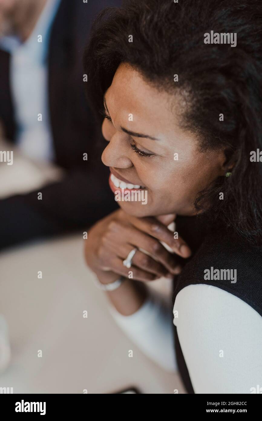 Femme d'affaires souriante avec main sur le menton dans la formation d'entreprise au bureau Banque D'Images