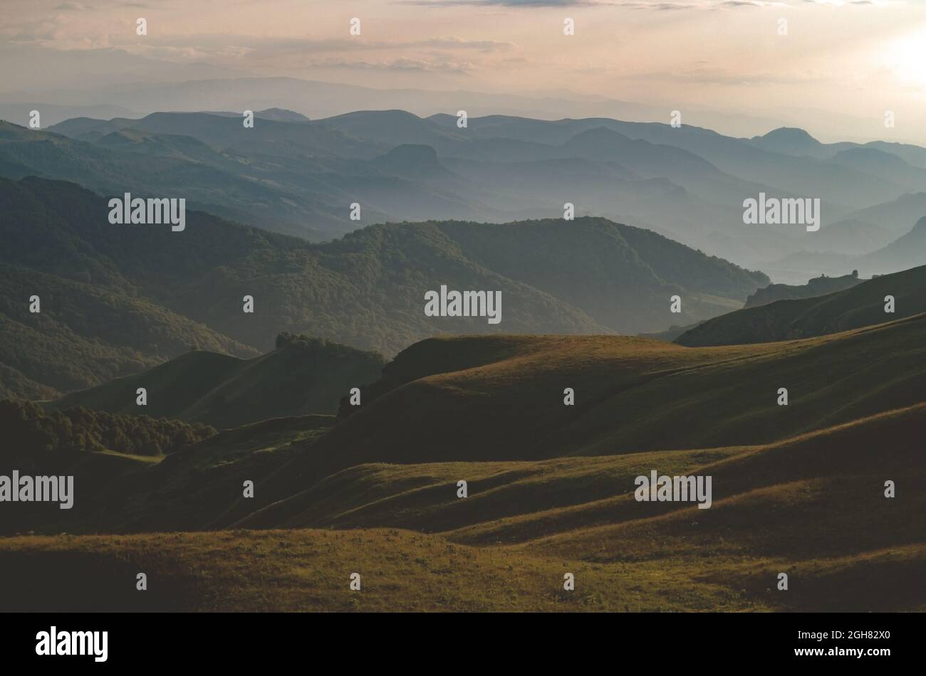 Magnifique panorama des collines verdoyantes et des montagnes au coucher du soleil. Col et route de montagne. Banque D'Images