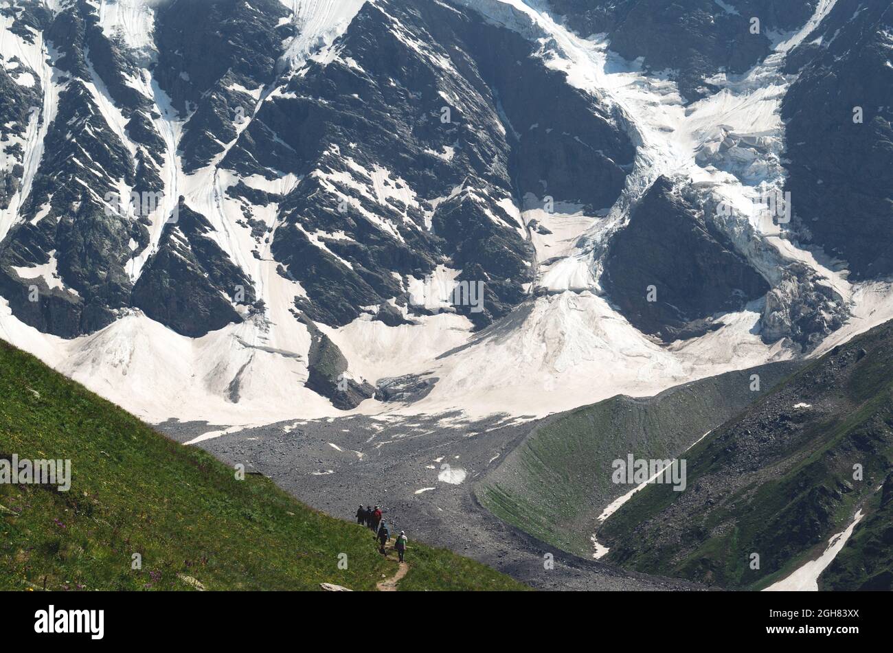 Un groupe de randonneurs avec des sacs à dos se promènent le long d'une chaîne de montagnes sur fond de montagnes enneigées. Le concept de voyage à la mountai Banque D'Images