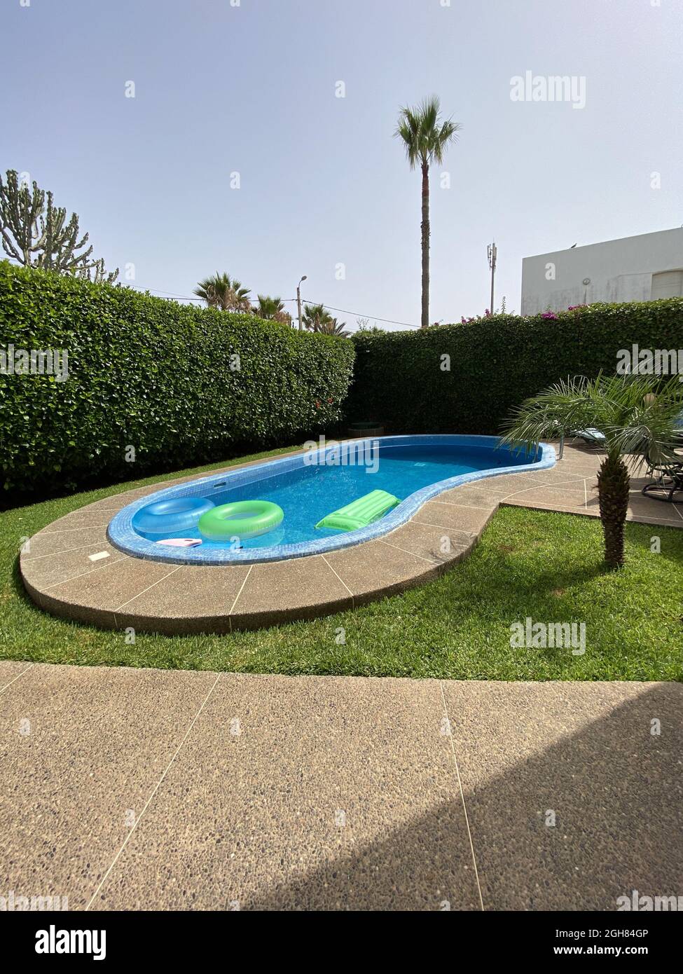 Piscine extérieure avec flotteurs verts et bleus entourés d'une clôture en herbe Banque D'Images