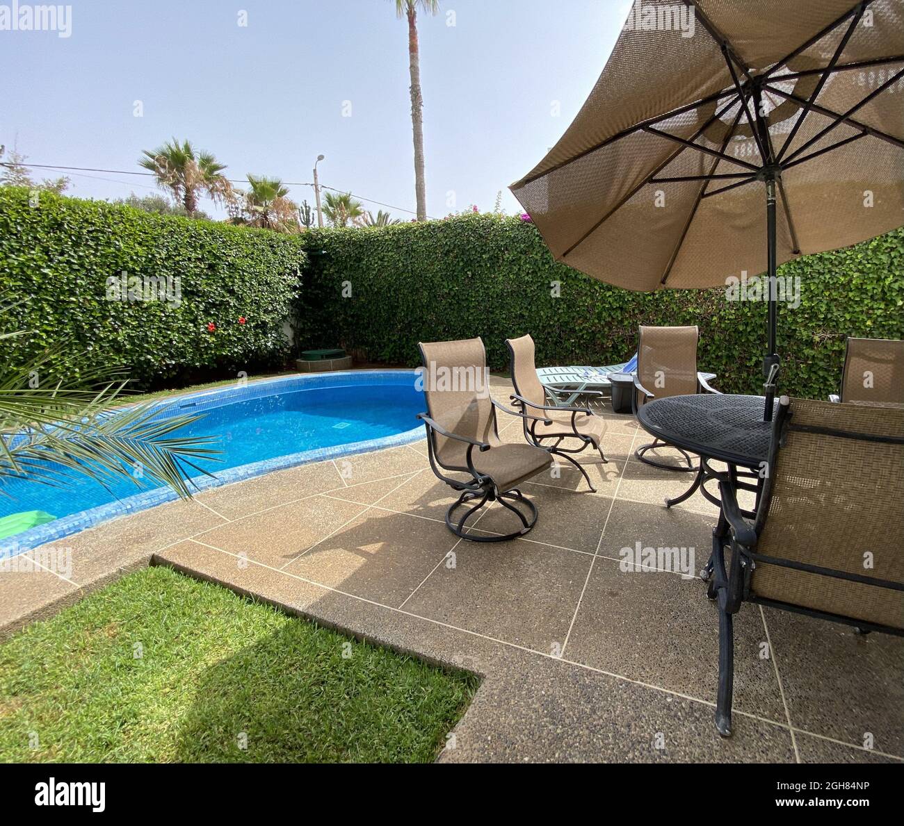 Piscine extérieure avec flotteurs entourée d'une clôture en herbe et d'une table avec chaises Banque D'Images