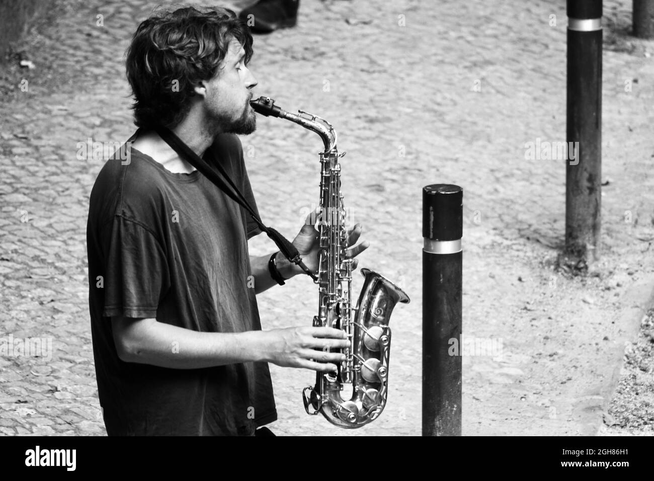 Sintra, Portugal; 02 septembre 2021: Jeune barbu jouant émotionnellement du saxophone dans la rue Banque D'Images