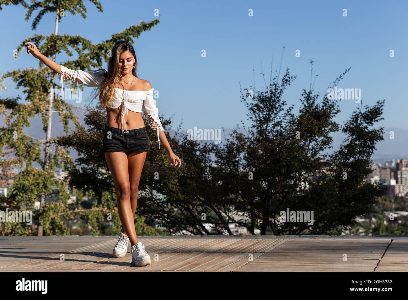 Jolie femme hispanique portant un haut à manches longues et un short à l'épaule lors d'une partie en plein air Banque D'Images