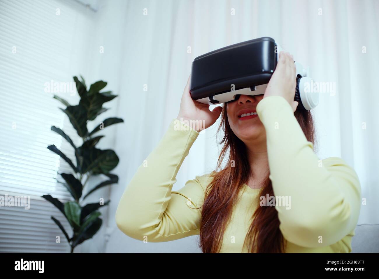 Jeune femme asiatique portant des lunettes de réalité virtuelle, la main touchant l'air.Casque VR.Concept VR. Banque D'Images