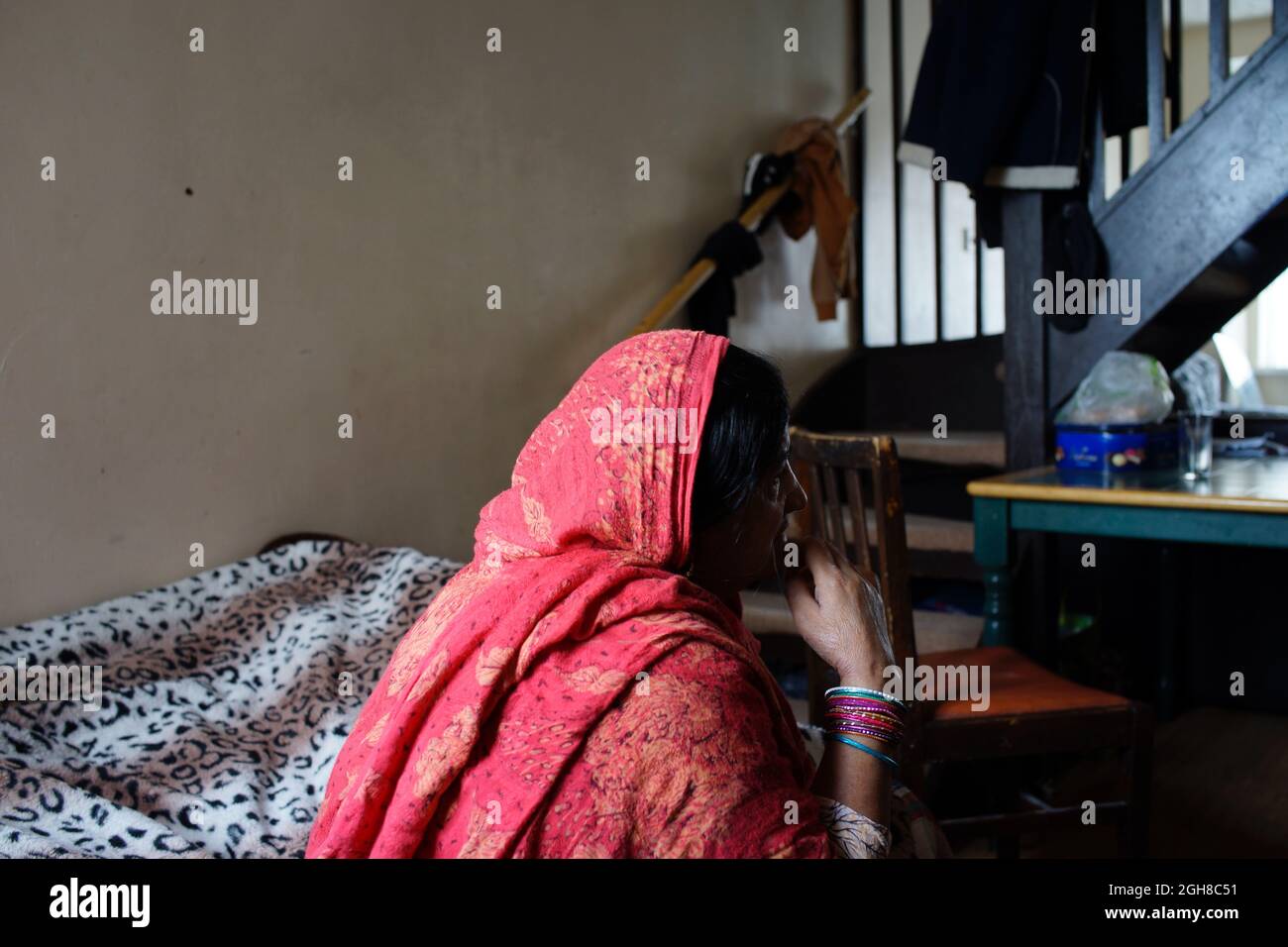 Femme pakistanaise immigrante, assise au lit, à la maison, Rugby, Angleterre, ROYAUME-UNI Banque D'Images