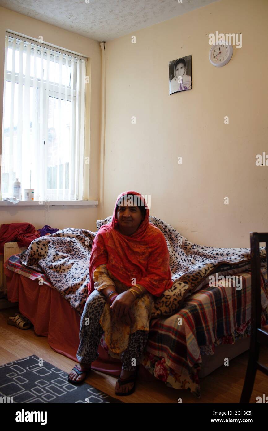 Femme pakistanaise immigrante, assise au lit, à la maison, Rugby, Angleterre, ROYAUME-UNI Banque D'Images