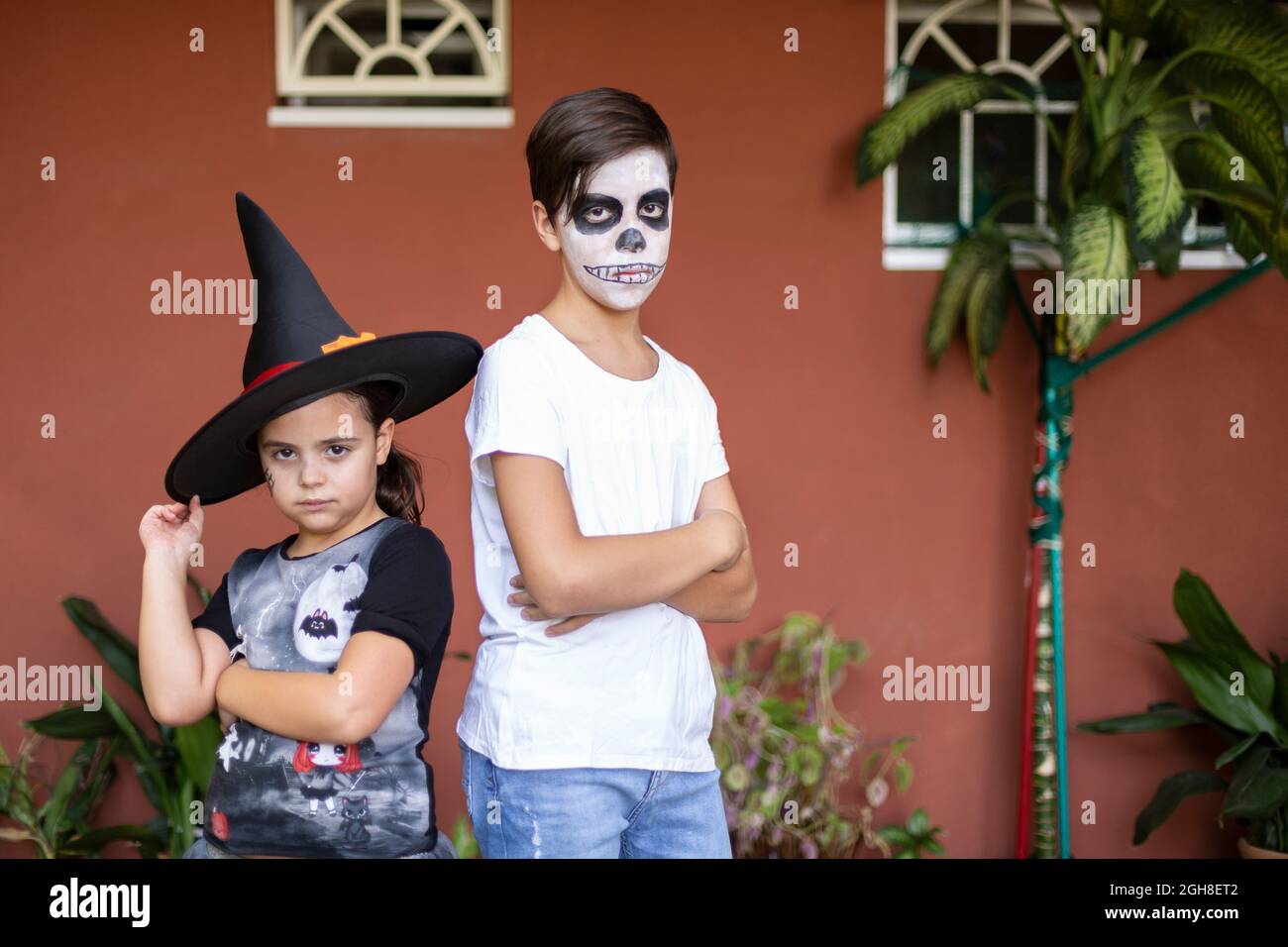 Garçon et fille caucasien posant avec leurs costumes à l'entrée de leur maison. Halloween Celebration concept. Banque D'Images