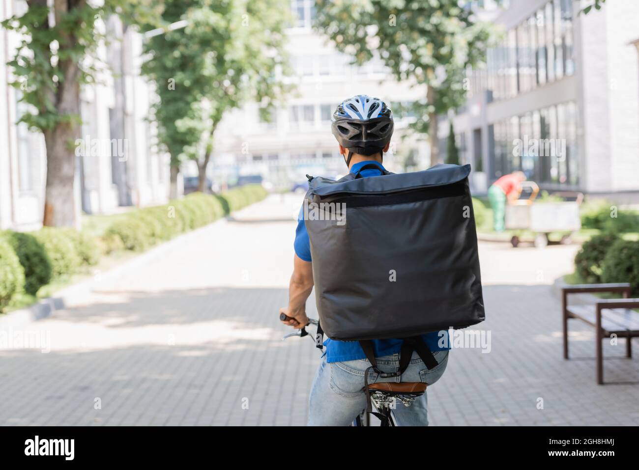 Vue arrière du coursier dans un casque et sac à dos thermo à vélo dans la  rue urbaine Photo Stock - Alamy
