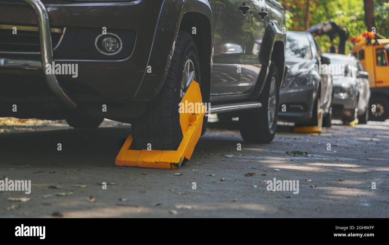 Une voiture garée avec une serrure à pneu jaune pour la violation de stationnement illégal. Zone de blocage des roues restreinte pour le stationnement. Banque D'Images