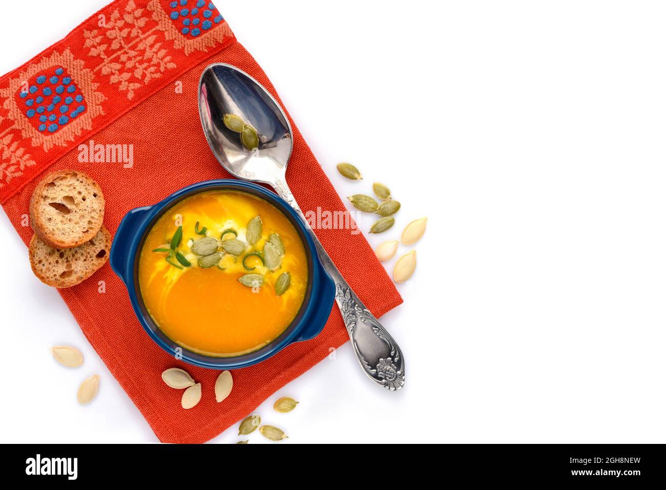 Vue de dessus du bol avec soupe à la crème de citrouille avec graines, crème et pain sur fond blanc Banque D'Images