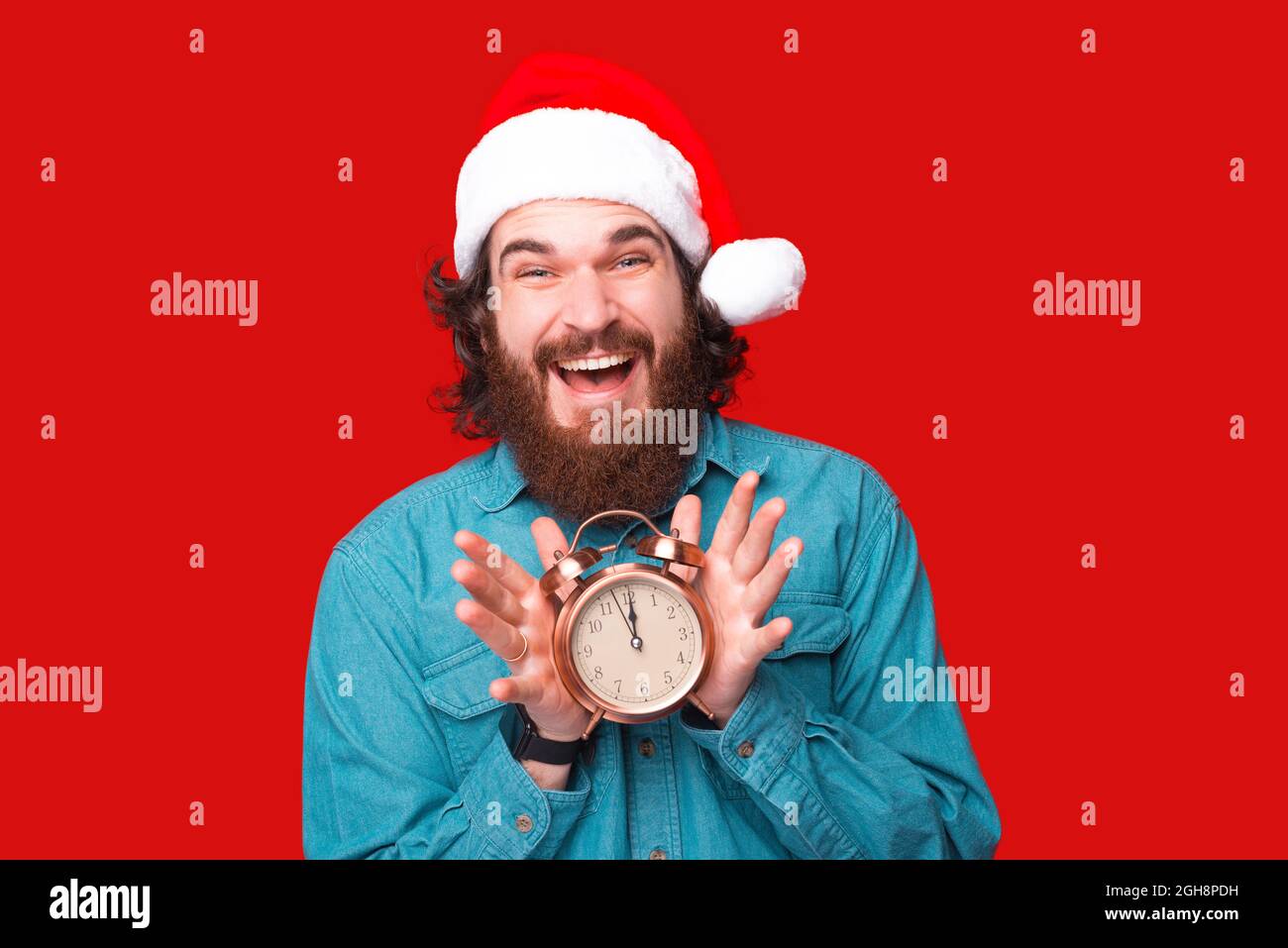 Joyeux barbu dans le chapeau du père noël tenant le réveil à 12 heures  Photo Stock - Alamy