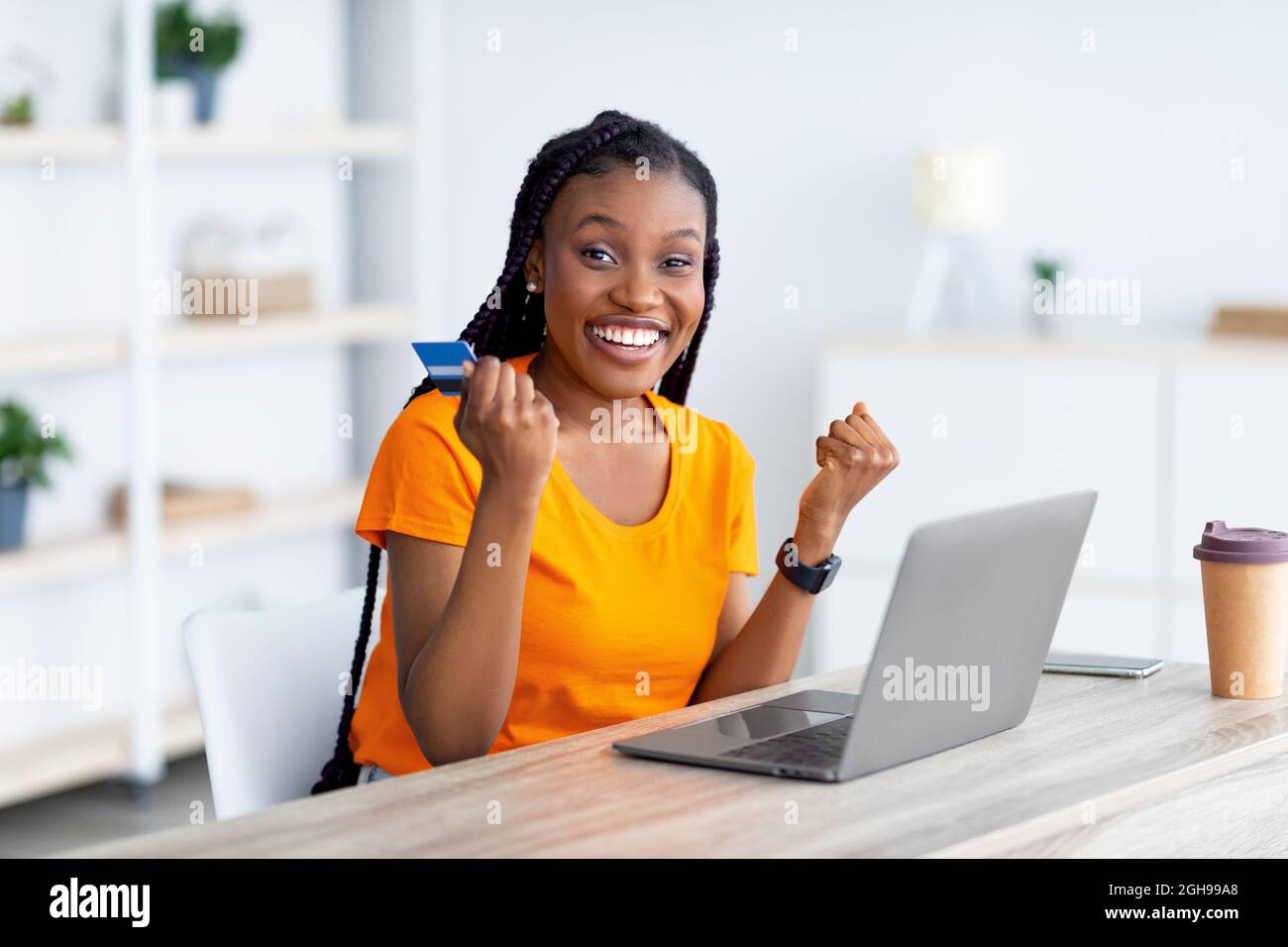 Femme noire excitee tenant la carte de credit devant l ordinateur portable faisant geste YES shopping en vente dans la boutique web de la maison Photo Stock Alamy