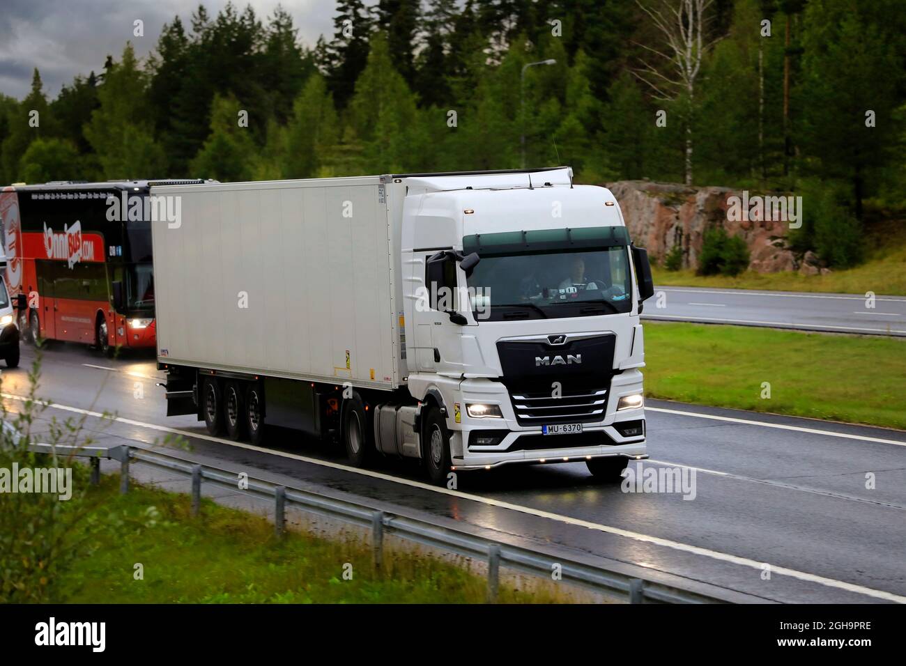 Nouveau camion blanc Man TGX 18.510 devant le camion semi-remorque FRC dans la circulation sur autoroute le matin pluvieux de l'automne. Salo, Finlande. 27 août 2021. Banque D'Images