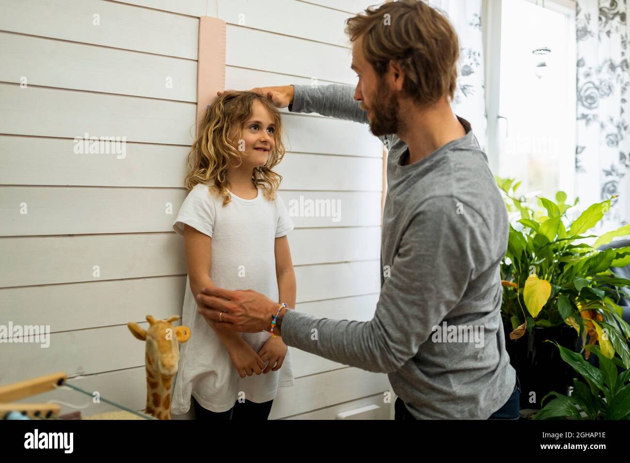 Père mesurant la taille de la fille à la maison Banque D'Images
