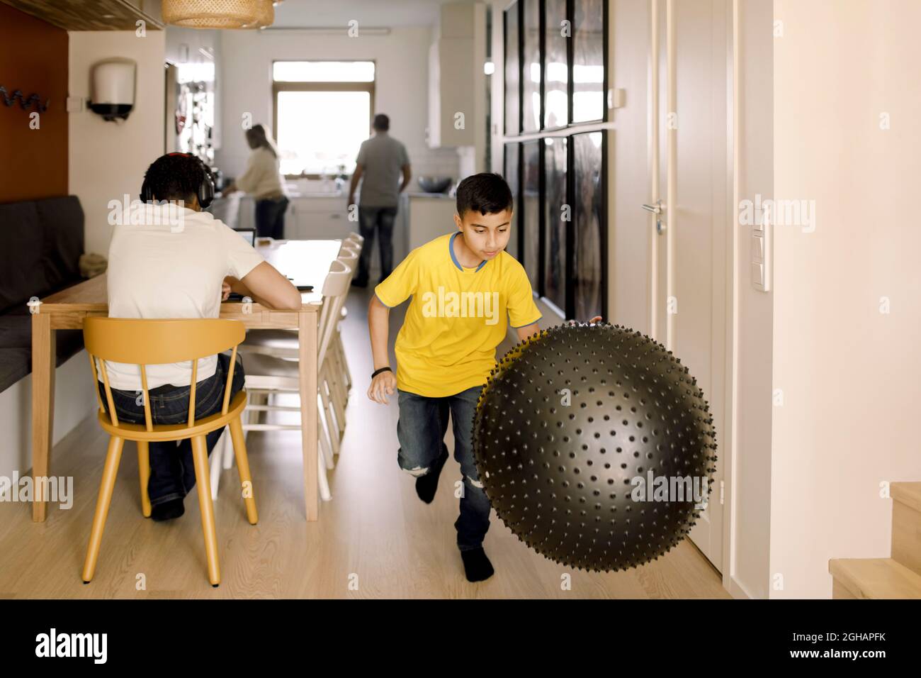 Pré-adolescent jouant avec le ballon de fitness à la maison Banque D'Images