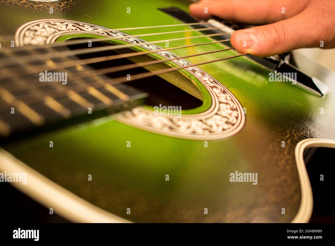 Main caucasienne touchant les cordes d'une vieille guitare verte Banque D'Images