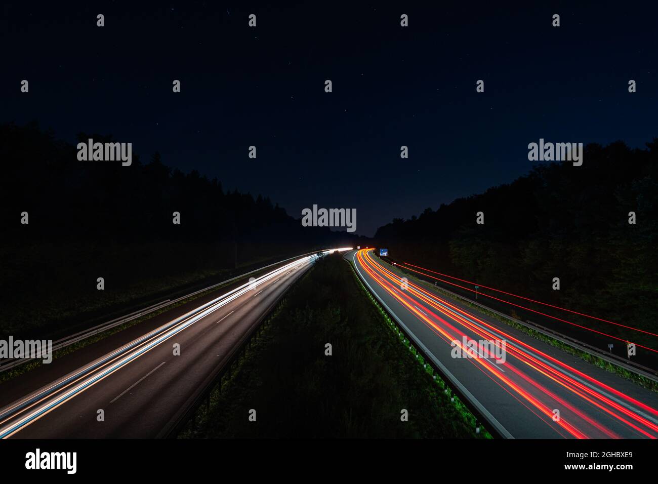 Des pistes lumineuses d'une autoroute de circulation depuis le devant de la voiture et les phares, passant rapidement le point de vue. Banque D'Images
