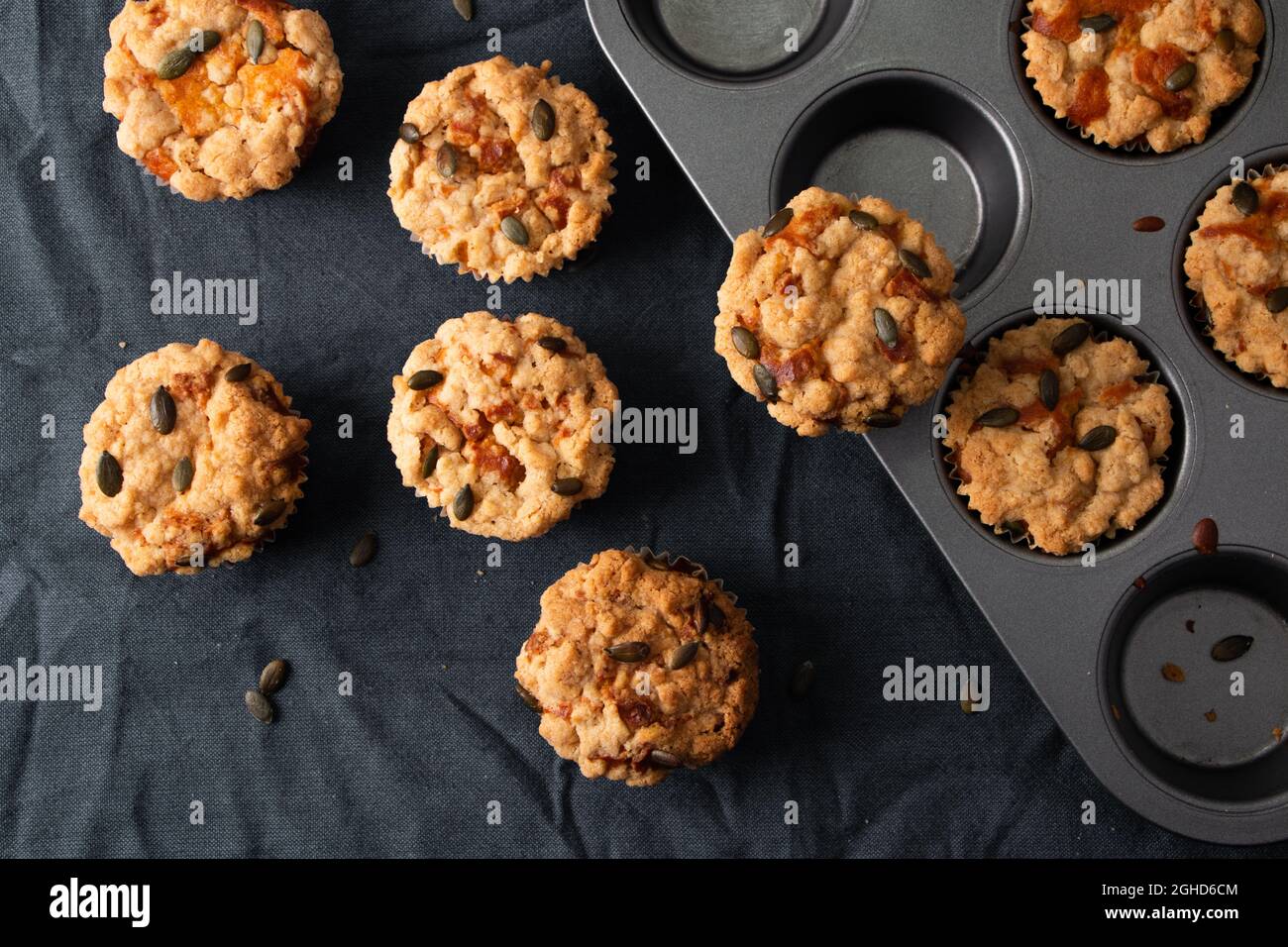 Muffins à la citrouille avec crumble et garniture de graines dans un moule à muffins sur un chiffon sombre Banque D'Images