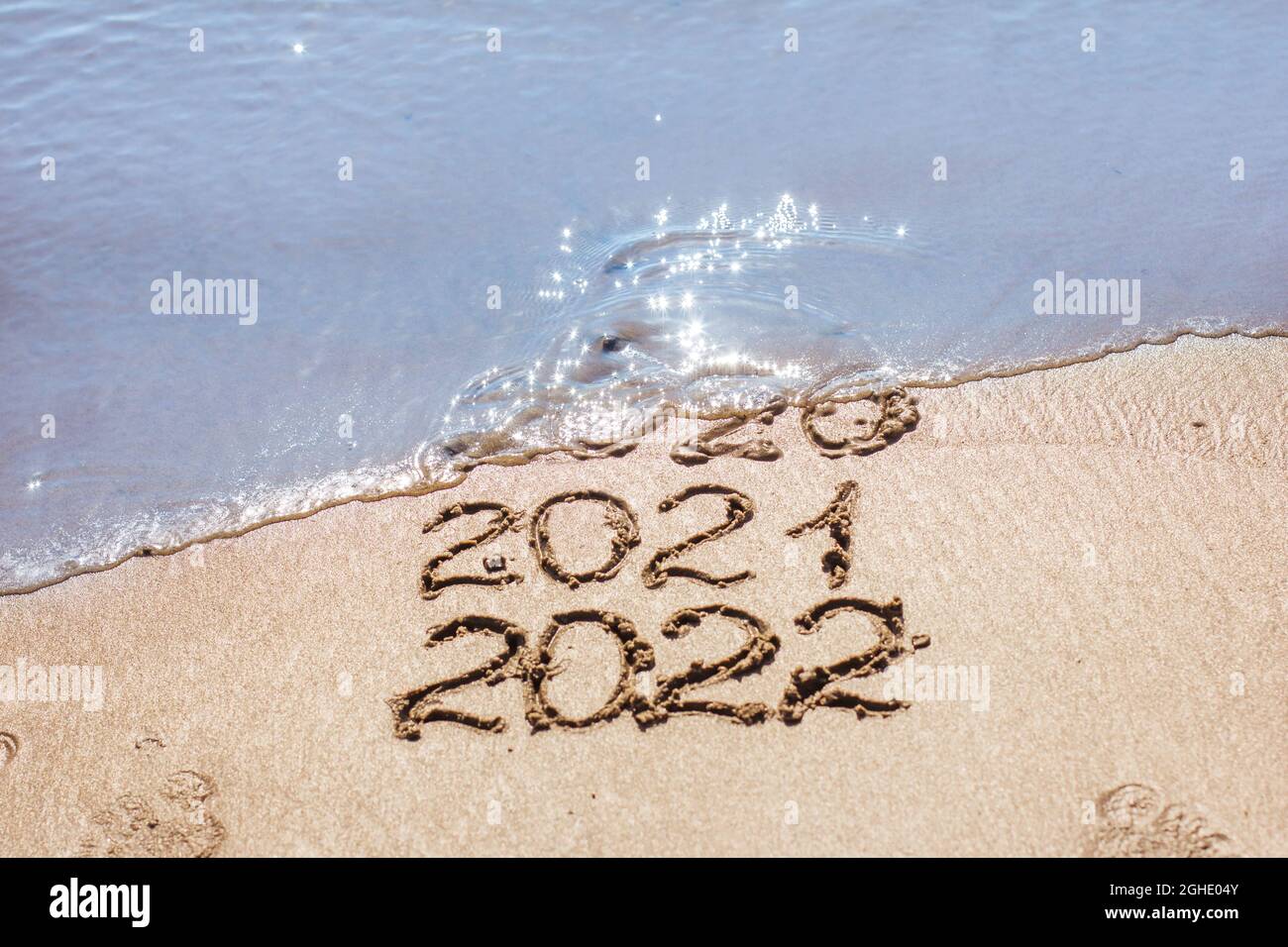 Les chiffres 2021, 2022 sont tirés sur le sable et lavés par la vague, le symbole de la nouvelle année, le changement de l'année Banque D'Images