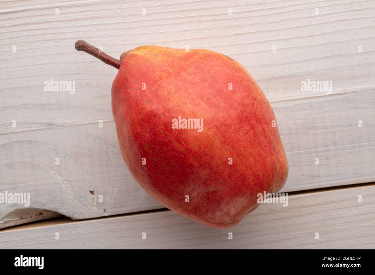 Une poire rouge mûre, gros plan, sur une table en bois, vue du dessus. Banque D'Images