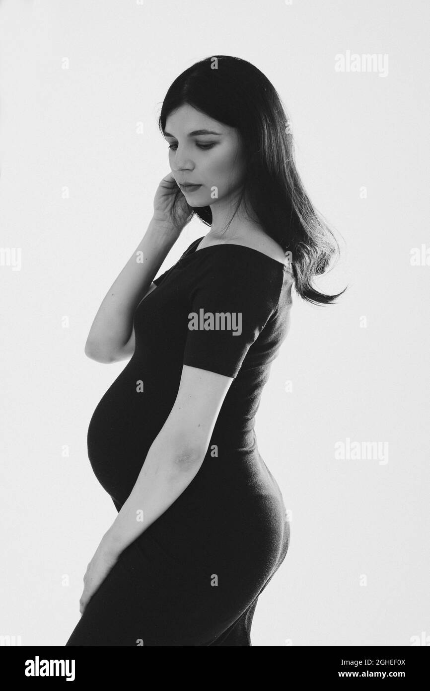 Belle brunette en robe noire s'attendant à bébé. Banque D'Images