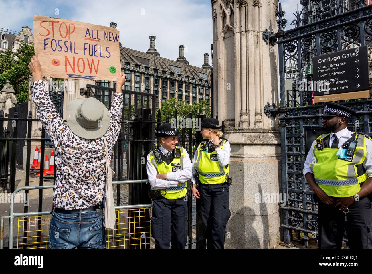 Extinction rébellion activiste avec étiquette Arrêtez tous les nouveaux combustibles fossiles et les officiers de police devant les chambres du Parlement, Parliament Square, Londres, Royaume-Uni 06.09.2021 Banque D'Images