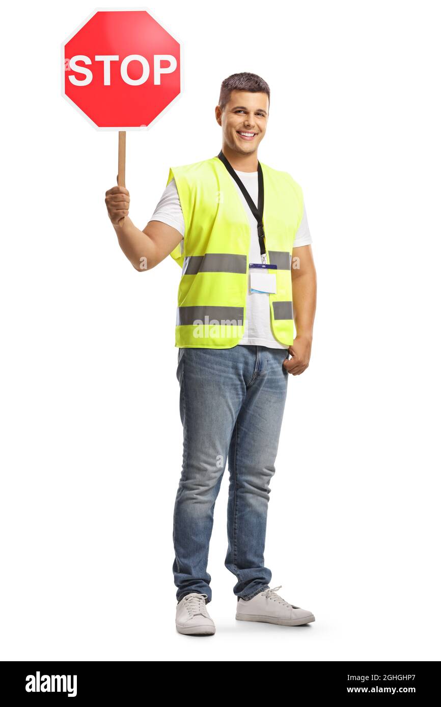 Jeune homme dans un gilet de sécurité avec un panneau d'arrêt de circulation regardant la caméra et souriant isolé sur fond blanc Banque D'Images