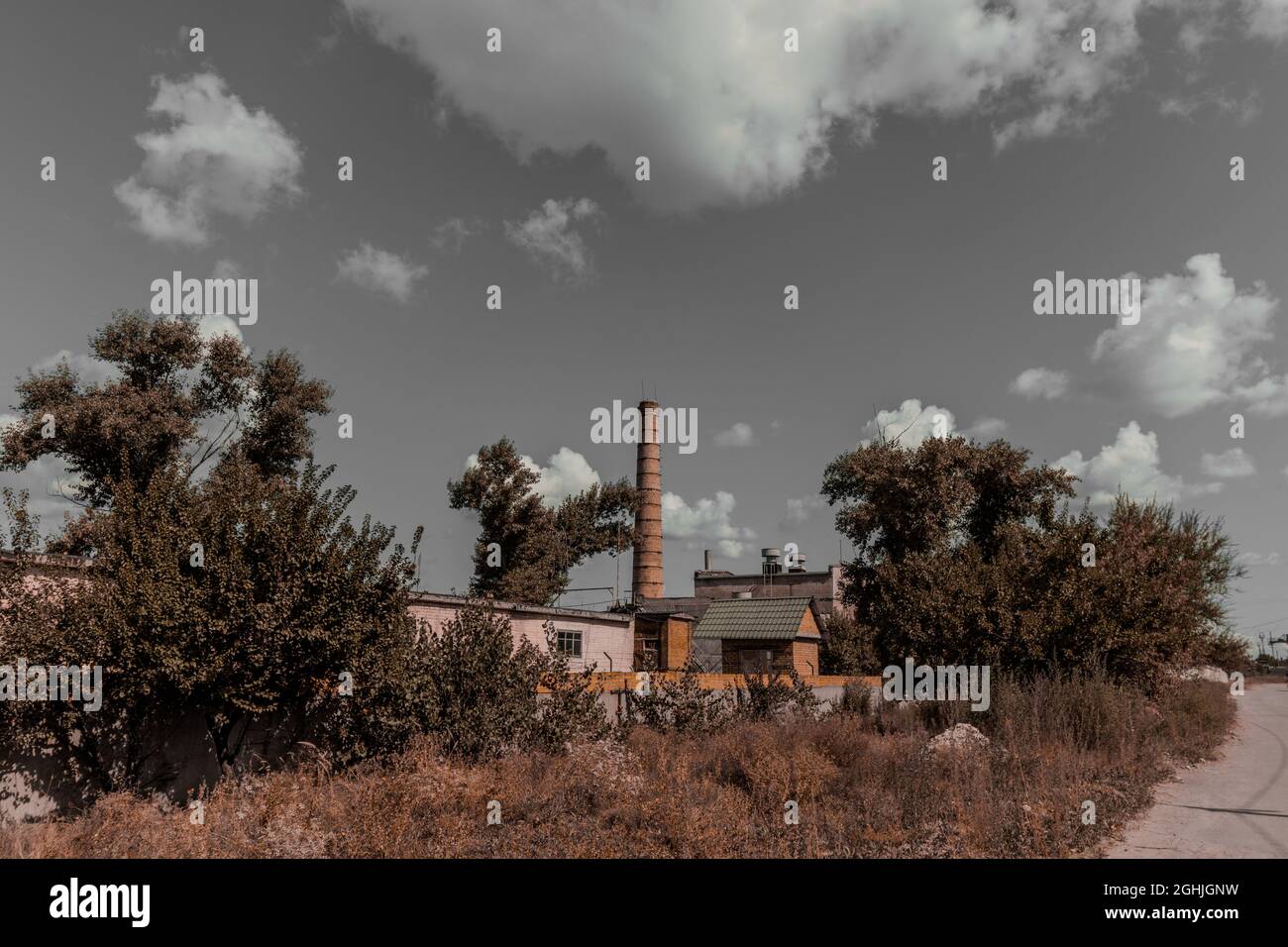 Sombre ancienne usine avec une cheminée contre un ciel gris. Banque D'Images