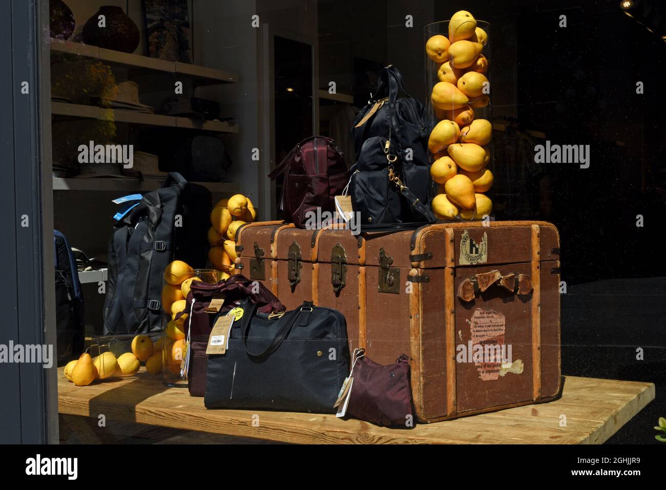 Un étalage de bagages de voyage comprenant des sacs neufs et un vieux coffre plus un vase en verre rempli de citrons Banque D'Images