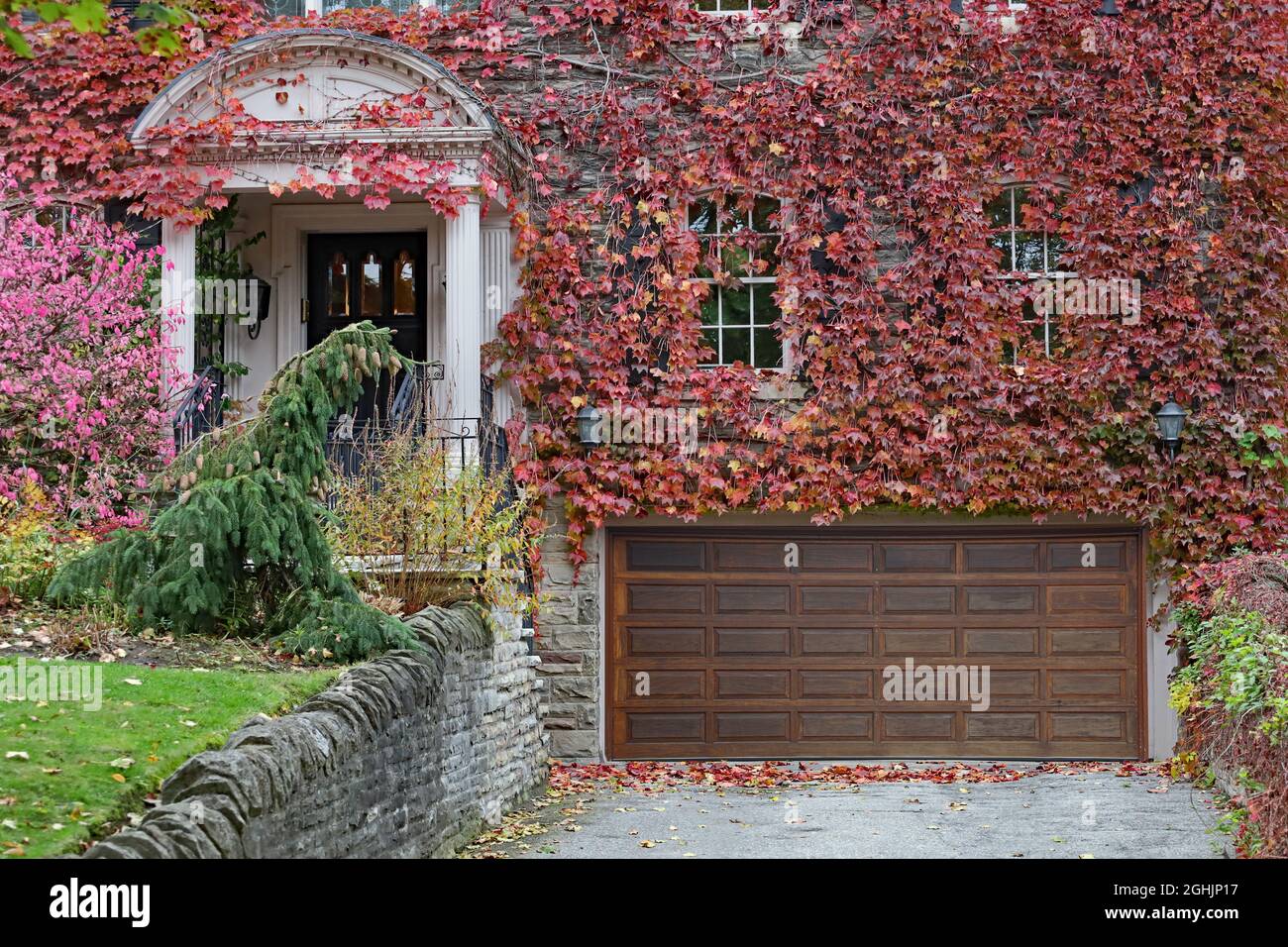 Façade de la vieille maison en pierre recouverte de vignes changeant de couleur en automne Banque D'Images