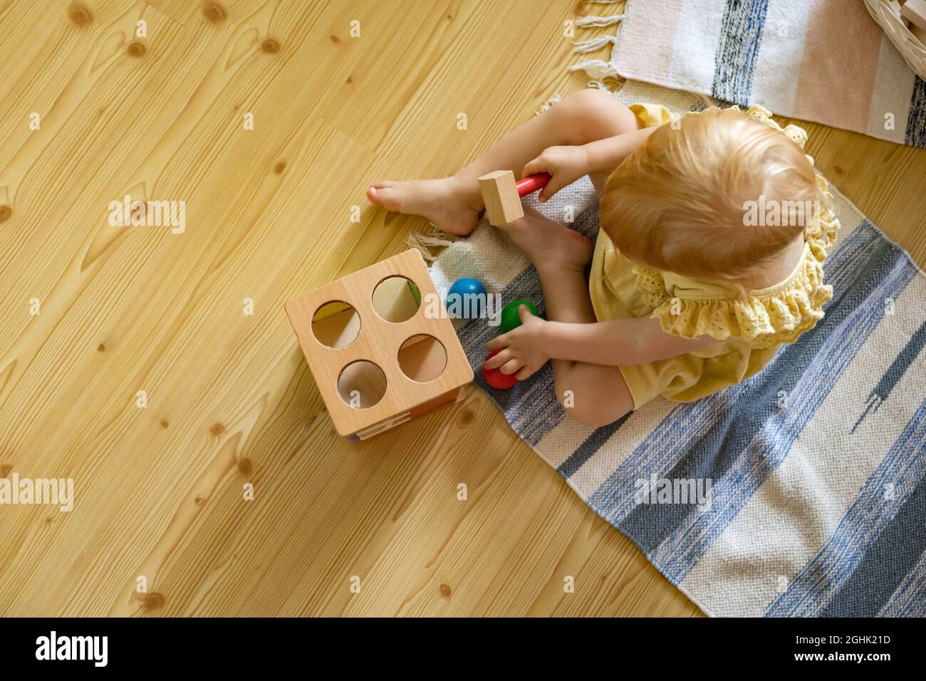 Bonne fille tout-petit frapper marteau en bois sur des boules colorées développement tôt jouet écologique Banque D'Images