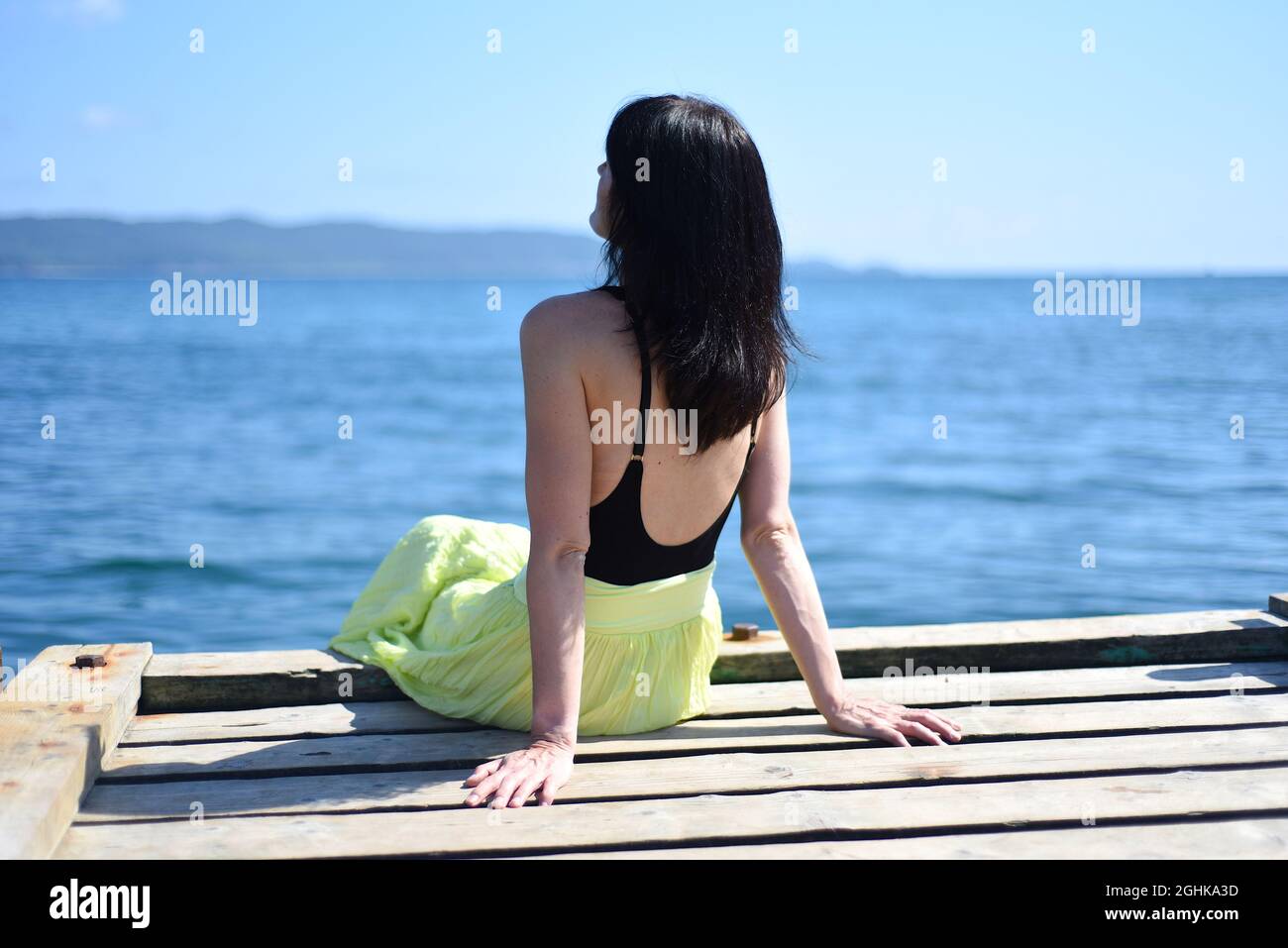 Femme russe de 45 ans assise sur un quai et regardant loin contre la mer japonaise Banque D'Images